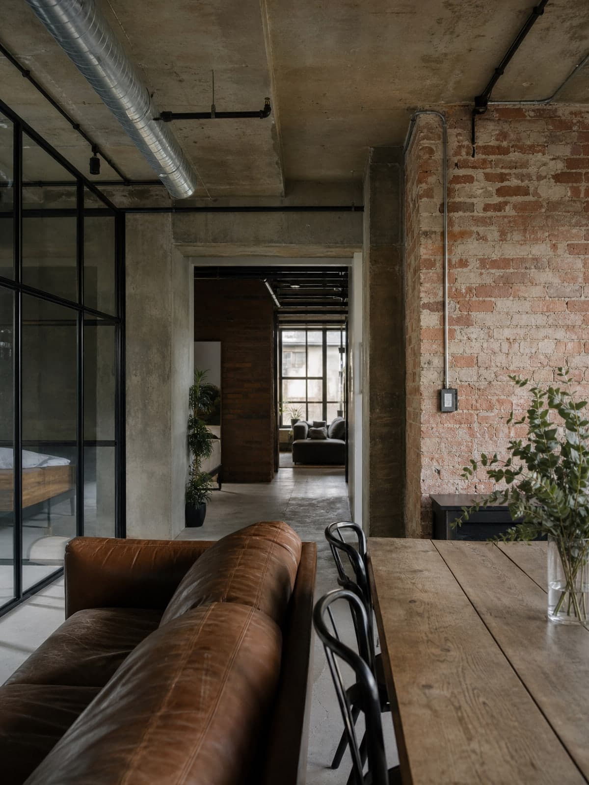 Loft interyeri: ochiq g'isht devor, beton shift va metall romlar